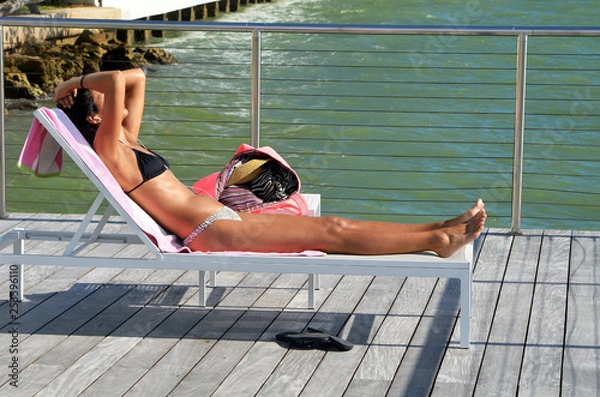 Fototapeta Sensuous Sunbather Reclining on a Sundeck Lounger