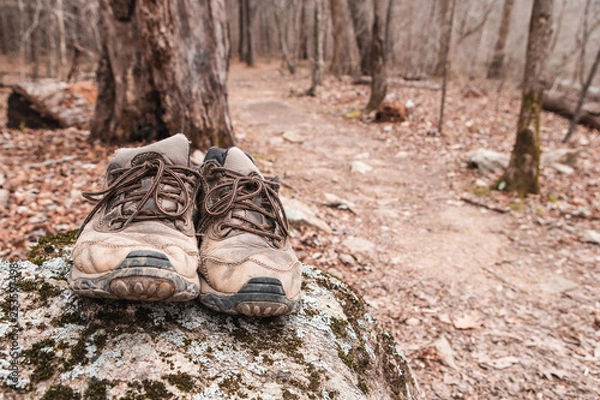 Obraz dirty hiking boots on rock beside trail