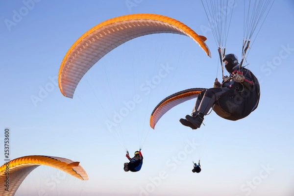Obraz Paraglide with a paraglider in a cocoon against the background of fields of the sky and clouds. Paragliding Sports