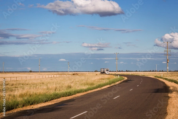 Fototapeta A curved outback road with an approaching truck in rural Australia on a sunny afternoon.  Copy space.
