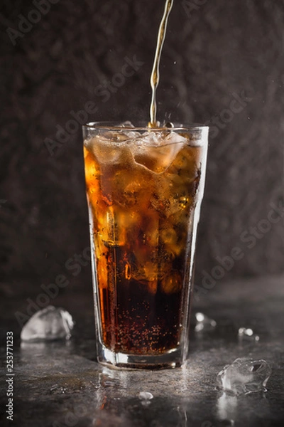 Fototapeta Glass of coke with ice on a dark background. Carbonated beverages. Selective fokus.