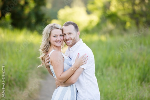 Obraz Attractive young couple embracing and smiling in green grass field