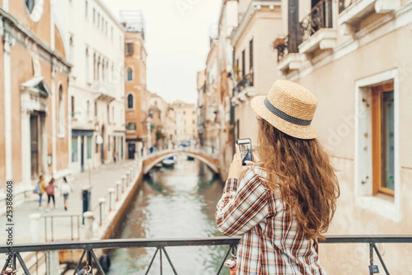 Obraz beautiful woman taking a photo on a mobile phone (smartphone) canal in Venice, Italy standing on a bridge