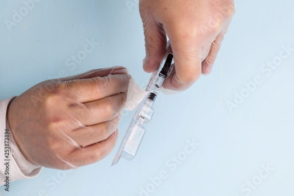 Fototapeta A male hand in a transparent medical nitrile glove holds a small syringe with medicine with a thin needle for subcutaneous administration. The concept of medicine, prevention of thrombophilia. IVF