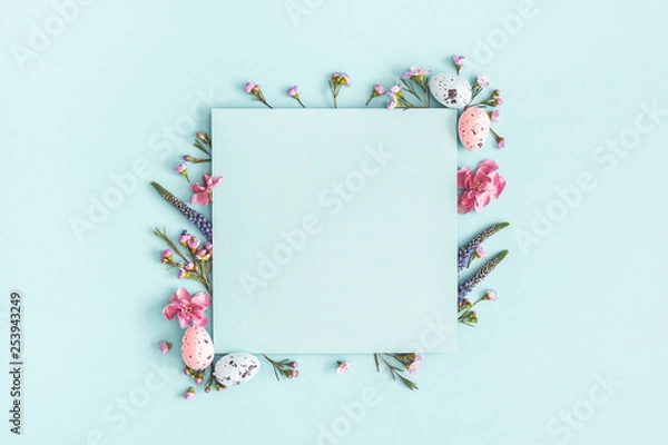 Obraz Easter composition. Easter eggs, flowers, paper blank on pastel blue background. Flat lay, top view, copy space