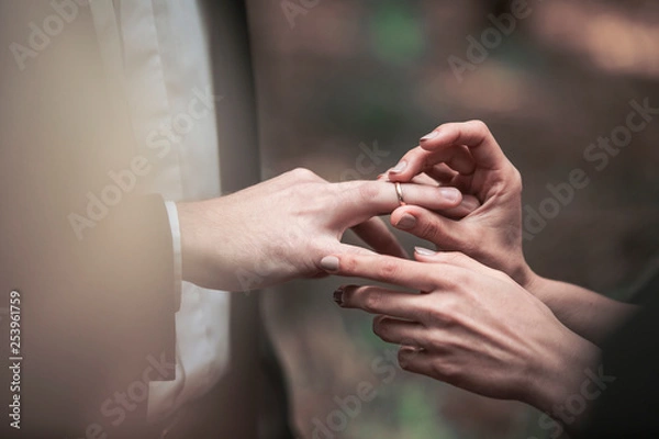 Fototapeta closeup of the groom places the ring on the bride's finger.