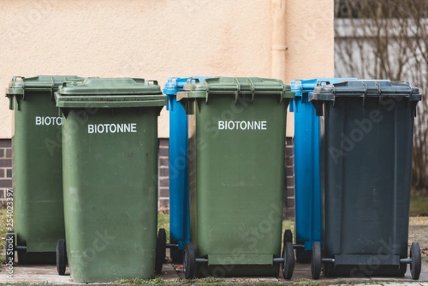 Fototapeta blue, black and green garbage bins in front of a house in Germany (Translation: Biotonne means biowaste)