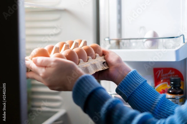 Obraz woman hands take eggs from the fridge