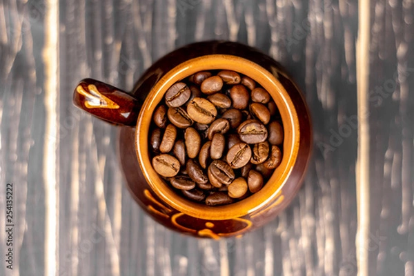 Obraz Coffee cup with roasted beans on black wooden background. Top view with copy space and soft focus.