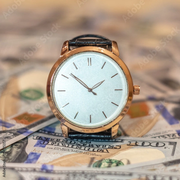 Obraz Management efficiency concept of time and money, wrist gold watch and US dollar banknotes.
