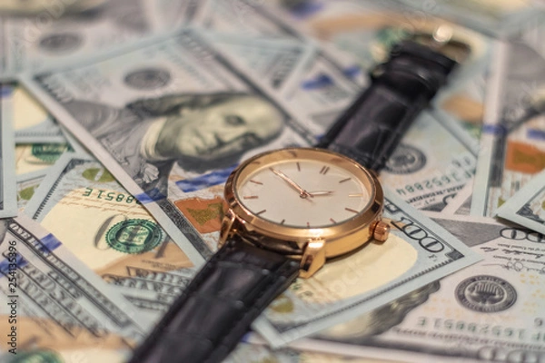 Obraz Wrist gold watch lie on the bills of 100 dollar money. Soft focus.