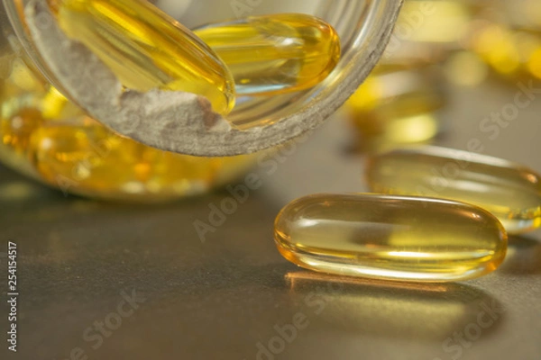 Fototapeta Gelatin capsules with the medicine are scattered across the table.