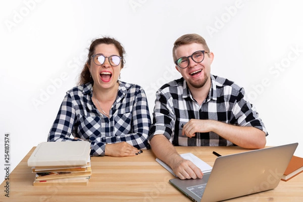 Fototapeta Nerds, geek, bespectacled and funny people concept - funny student couple in glasses sitting at the table