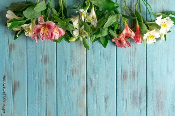 Fototapeta Frame for the text of congratulations with natural flowers of Alstroemeria on a wooden background. Design greeting card with natural colors. Background for text with alstromeria. Flat lay, top view.