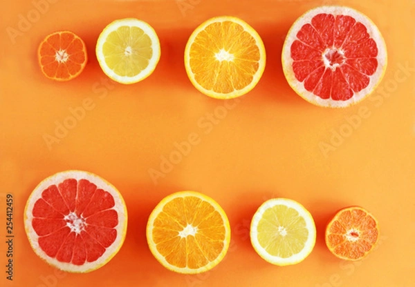 Fototapeta halved citrus fruits in a row on orange colored background