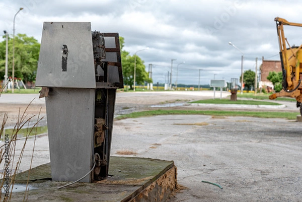 Fototapeta Old dirty gas station, rusted, old and abandoned gas dispenser with a landscape of a death town. The end of fossil energy