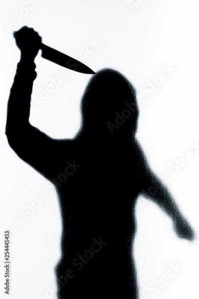 Fototapeta Dangerous man behind frosted glass with a knife in his hand. Halloween. Black and white image.