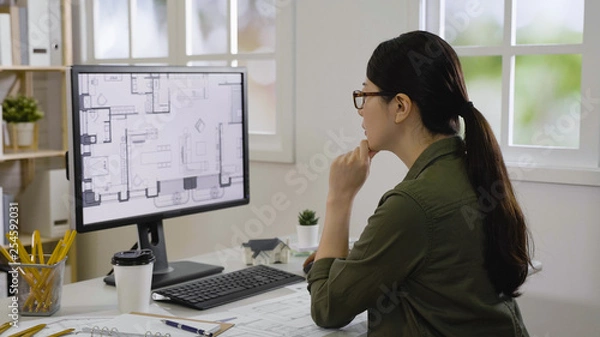 Fototapeta Blueprint architect construction project sketch concept. side view of elegant female engineer thoughtful staring on computer monitor with plan floor thinking. asian woman interior designer thinking.