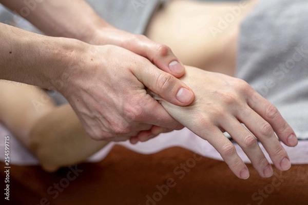Fototapeta Beautiful young woman is receiving a hand massage at a massage salon