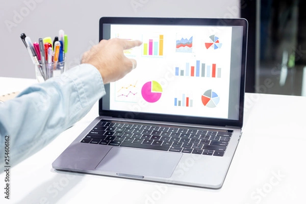 Fototapeta Businessman workspace laptop with coffee cup ,computer screen graphics and chart at office room