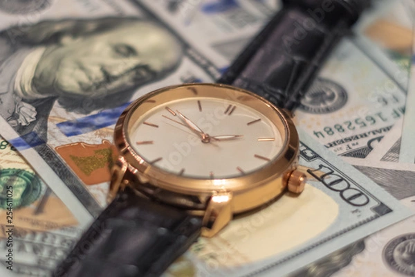 Obraz Wrist gold watch lie on the bills of 100 dollar money. Soft focus.