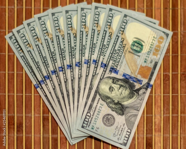 Obraz The stack is 100 dollar bills USD spread out like a fan, on a wooden background.