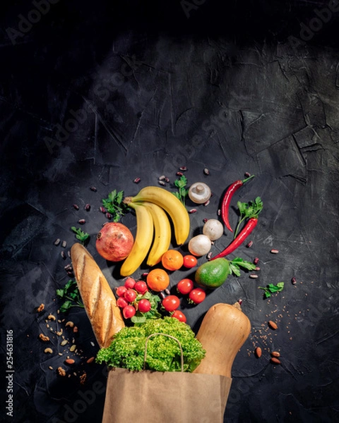 Fototapeta Healthy food in full paper bag of different products vegetables and fruits on dark background