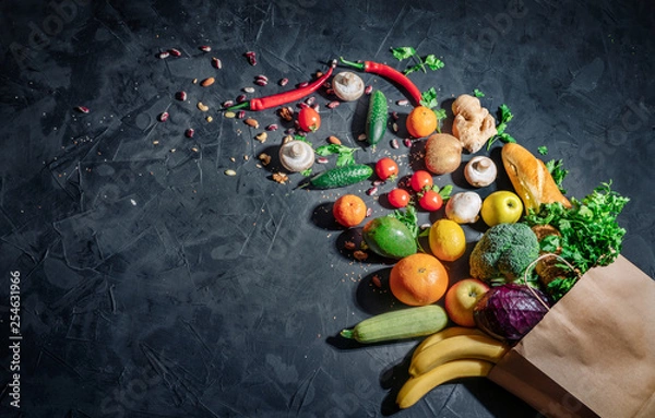 Fototapeta Healthy food in full paper bag of different products vegetables and fruits on dark background