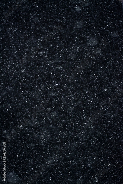 Fototapeta Artificial snow falling on a black background as overlay