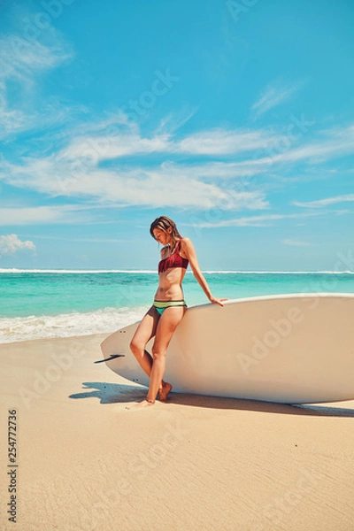 Fototapeta Beautiful surfer girl in bikini with surfboard enjoying on the beach. Summer concept.