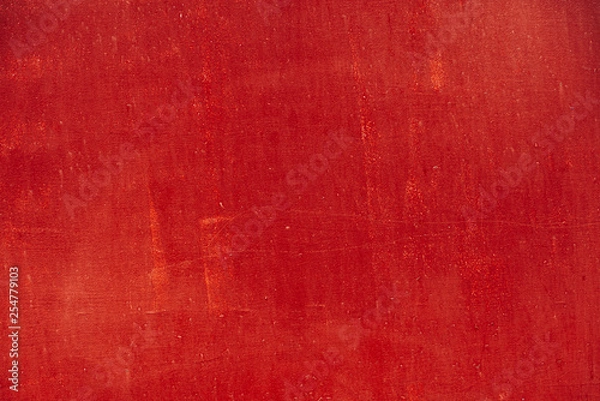 Fototapeta Imperfect metallic plate. Scratched vivid red paint surface close-up. Damage texture in macro. Grungy metal panel. Textured background. Stains on rough faded uneven concrete wall. Old bright red paint