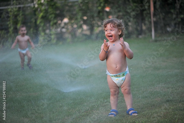 Obraz Baby getting wet on a garden in summer