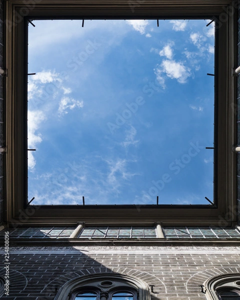 Fototapeta Window to the sky. View upstairs from courtyard of vintage house in Florence, Italy. Very interesting angle. Square frame with falling sun rays.