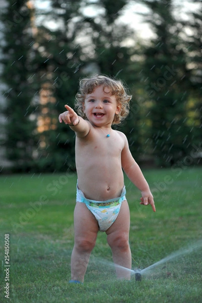 Obraz Baby getting wet on a garden in summer