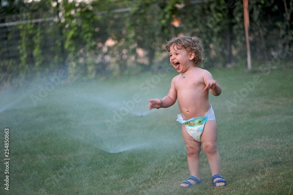 Obraz Baby getting wet on a garden in summer