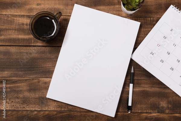 Obraz top view image of open notebook with blank pages next to cup of coffee on wooden table. ready for adding text or mockup.