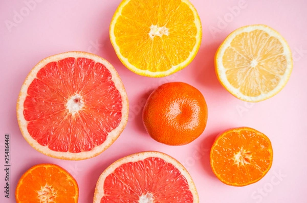 Fototapeta Flat lay of cut ripe juicy citrus fruits on pink background. Citrus pattern.
