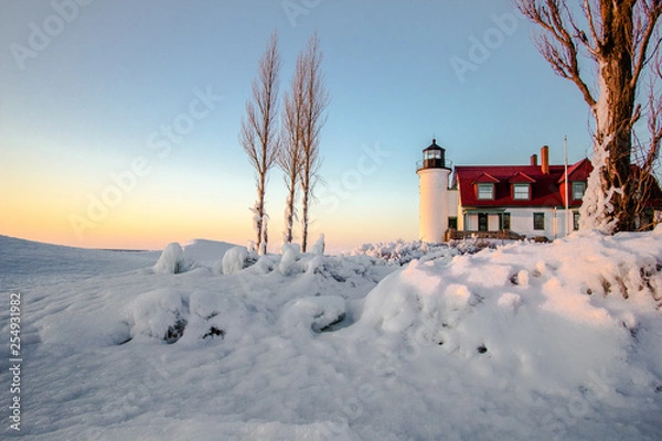 Obraz Winter Lighthouse On The Great Lakes. Beautiful winter landscape on the  coast of Lake Michigan with the Point Betsie Lighthouse bathed in the glow of the setting sun.