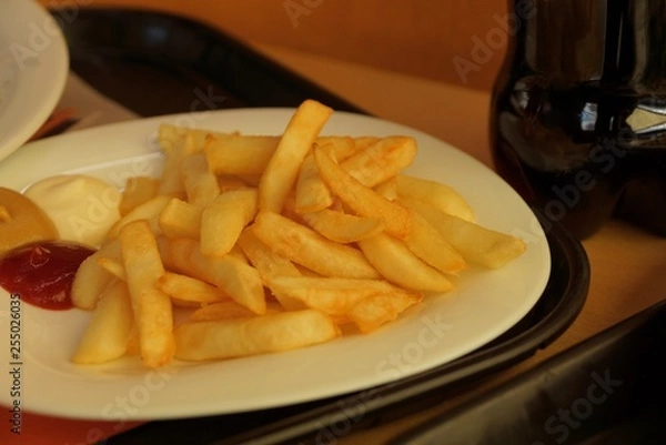 Fototapeta fried potatoes on a white plate with sauces on a brown table