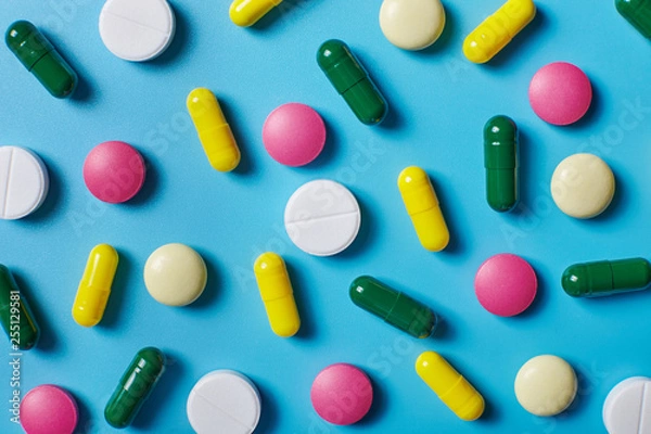 Fototapeta Multicolored pills on blue background. Pattern.