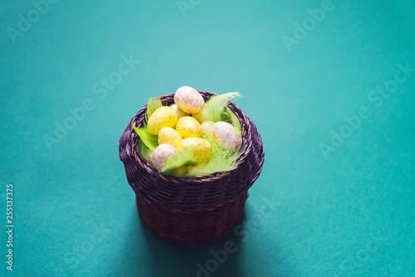 Fototapeta Easter composition with traditional decor. Small colorful eggs in wicker basket on soft background.