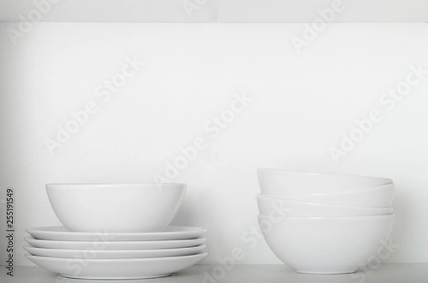 Fototapeta White plates and bowls on a shelf in the cupboard. Kitchenware, clean dishes
