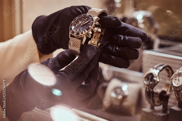 Obraz Close-up of the seller's hands in gloves shows the exclusive men's watch from the new collection in the luxury jewelry store