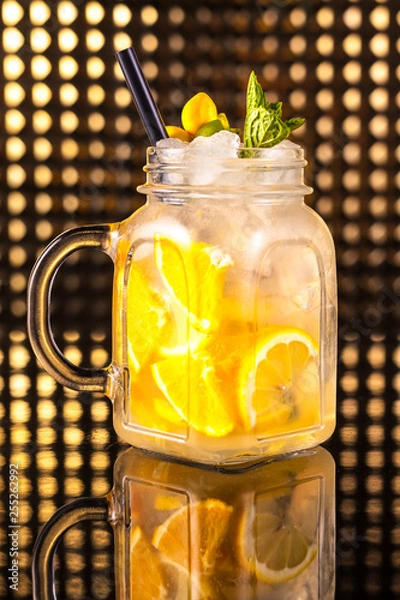 Fototapeta Yellow fruit cocktail lemonade with fresh lemon in vintage jar