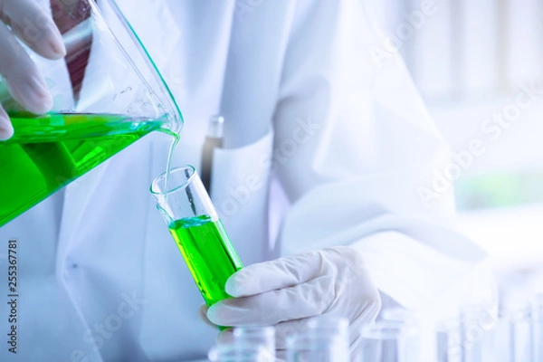 Obraz Green liquid substance was pouring into test tube by  scientist or chemist in science experiment  at laboratory . Research and scientific discovery concept.