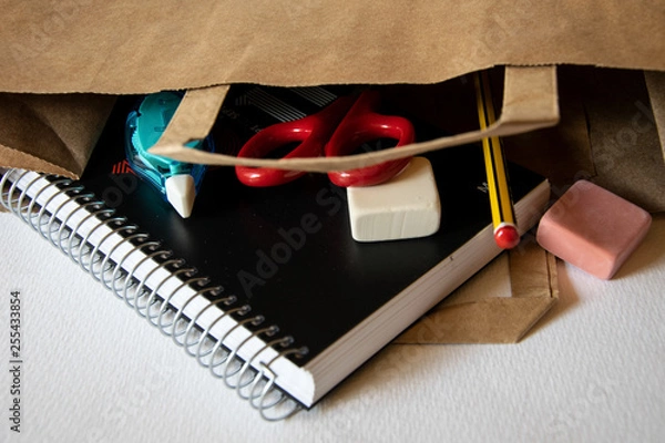 Fototapeta Vaciando la bolsa con objetos escolares después de la compra.