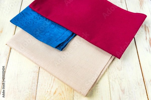 Fototapeta close up of cloth napkins of beige, blue and burgundy colors on rustic white wooden table. Shallow depth of field.