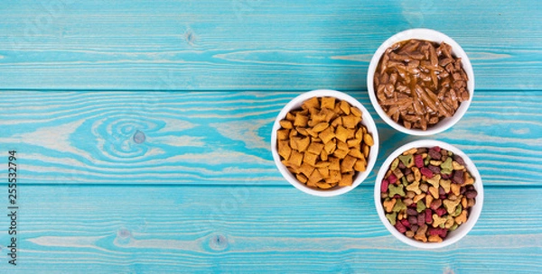 Fototapeta Various cat food. Dry and wet cat food. Copy space. Bowls with cat food on wooden background.