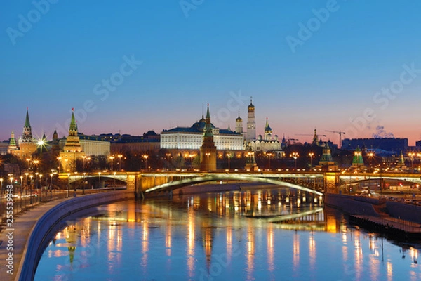 Obraz Illuminated Moscow Kremlin and Bolshoy Kamenny Bridge in the rays of rising sun. View from the Patriarshy pedestrian Bridge in Russia. Morning urban landscape in the blue hour
