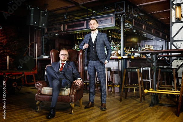 Fototapeta Two successful stylish business partners in a pub. Two men in suits in the exclusive nightclub